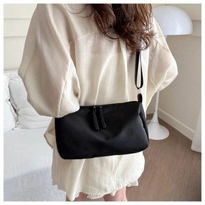 Minimalist black oxford crossbody bag with dual zipper detail worn by a model