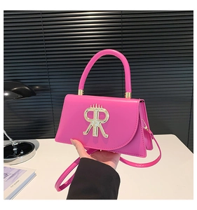 Détail du sac à bandoulière rose fuchsia avec logo couronne dorée et poignée ronde