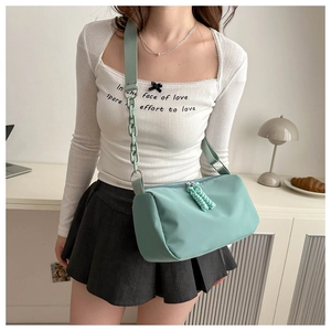 Detail of mint green oxford crossbody bag with woven knot zipper and chain strap
