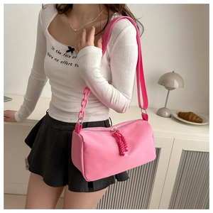 Pink nylon crossbody bag detail with chunky plastic chain and adjustable woven strap