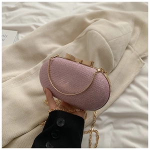 Detail of pink glitter evening clutch with golden bow clasp and delicate chain strap