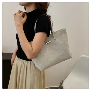 Detail showing woven texture and silver metal patch on minimalist canvas tote bag