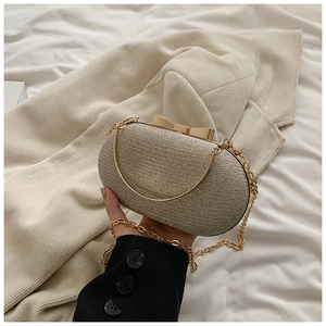 Detail of champagne gold sequin clutch with bow clasp and golden metal chain strap