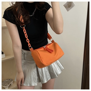 Detail of orange nylon cylinder bag with decorative plastic chain strap and zipper