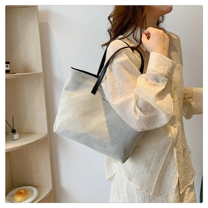 Minimalist canvas tote bag with black leather straps shown on shoulder for daily commute