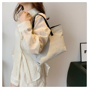 Side view of large canvas tote bag with black straps on a person for casual commuting
