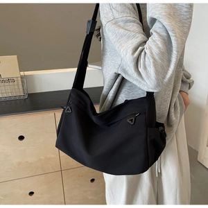 Detail of minimalist black nylon tote bag featuring unique triangle zippers and wide strap