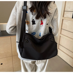 Detailed view of black nylon tote bag with adjustable shoulder strap and zipper pockets