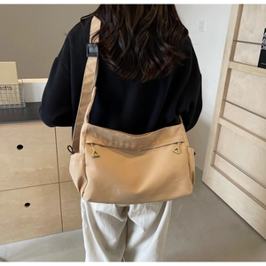 Detail of khaki nylon crossbody tote bag showing dual front pockets and shoulder strap