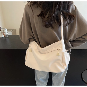 Detailed back view of a large cream nylon tote bag with functional drawstring side pockets