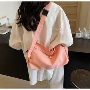 Detailed view of pink nylon crescent bag with adjustable wide strap and minimal hardware