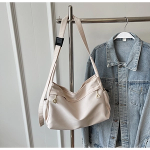 Detail of off-white nylon tote bag with triangle metal zippers and adjustable black buckle