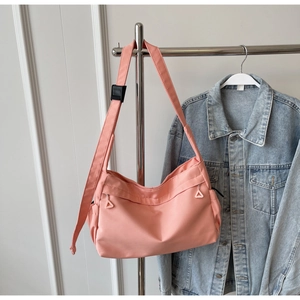 Detailed close-up of pink nylon tote bag featuring front zipper pockets and shoulder strap