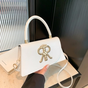 Sac bandoulière en cuir blanc avec logo R doré et couronne, tenu à la main par une personne