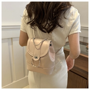 Détails du dos d'un mini sac à dos beige avec bretelles en chaîne et fermoir pivotant