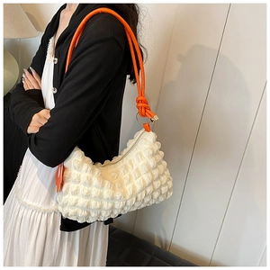 Detail of white bubble texture bag with orange knotted shoulder strap and zipper