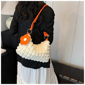 Detail of white bubble texture shoulder bag with bright orange flower charm and strap
