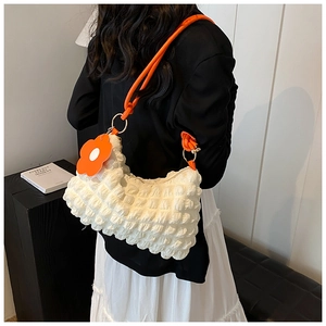 Detailed bubble textured white shoulder bag with orange strap and floral charm accessory