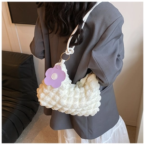 Detail of white popcorn texture fabric on shoulder bag with purple flower charm accessory