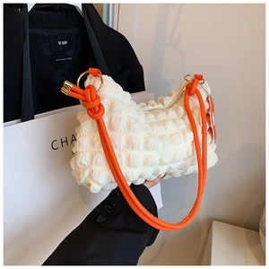 Detail of white bubble pleated handbag with orange strap and gold hardware accents