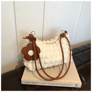 Detail of white bubble textured underarm bag with brown handle and flower charm