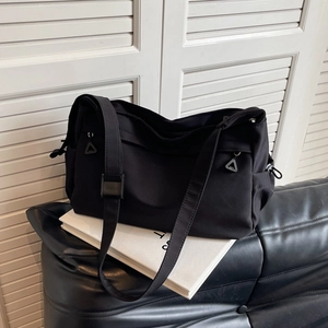 Large black nylon tote bag with adjustable straps and side drawstring on a white background