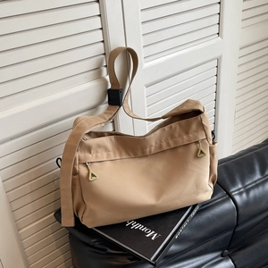 Khaki large capacity oxford tote bag with gold triangle zippers on a black sofa