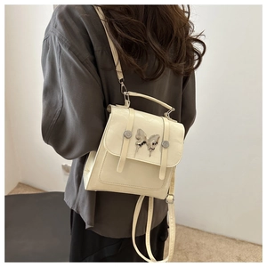 Cream white leather backpack with silver butterfly detail worn by a model in a back view
