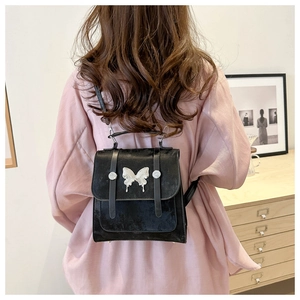 Detail of black mini backpack with silver butterfly buckle and matte texture