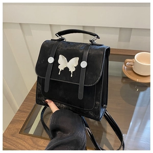 Detailed shot of a black vintage textured bag with a silver butterfly and metal buckles