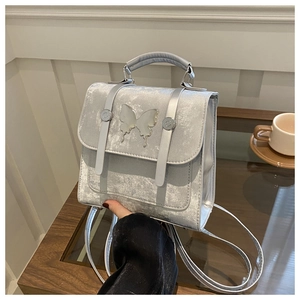 Detail of silver velvet backpack with decorative butterfly and polished metallic finish