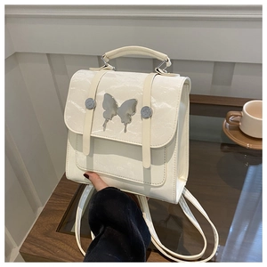 Detailed close-up of cream white PU leather backpack with a large silver butterfly buckle