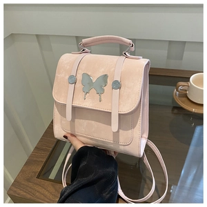 Macro detail of pink suede mini backpack showing silver butterfly metal ornament