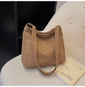 Close-up of brown corduroy tote bag texture with double straps on a soft sofa