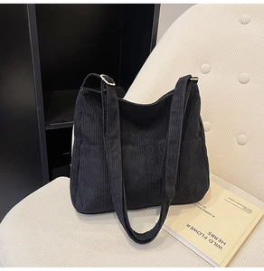 Detail of black corduroy tote bag showing adjustable metal buckle and textured fabric
