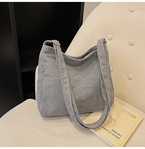 Detail of gray corduroy tote bag showing ribbed texture and two front pockets