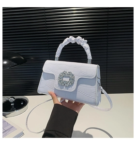 Detail of white crocodile embossed leather bag with large crystal buckle and pleated handle