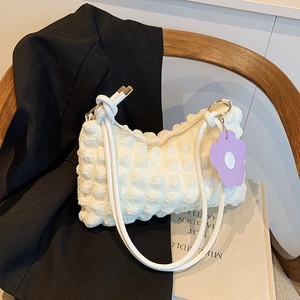 Chic cream bubble popcorn texture shoulder bag with flower charm on a black blazer
