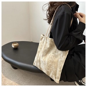 Detail view of champagne velvet tote bag with elegant leaf patterns and slim shoulder straps
