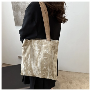 Detail of metallic beige tote bag with leaf patterns and round gold magnetic clasp