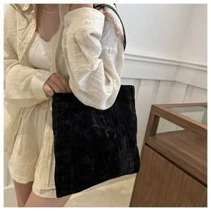 Detail of black velvet tote bag with embossed texture worn over the shoulder
