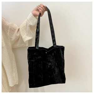 Close-up of black velvet tote bag texture and straps for minimalist commute