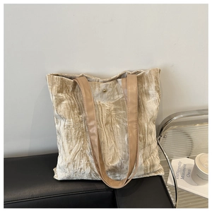 Detail of champagne gold pleated tote bag showing leaf patterns and magnetic closure