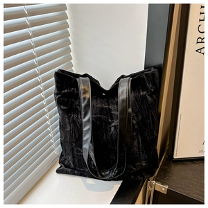 Detail of black velvet tote bag with embossed leaf texture and glossy leather straps