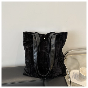 Detailed view of black crushed velvet tote bag with leather strap and gold snap button