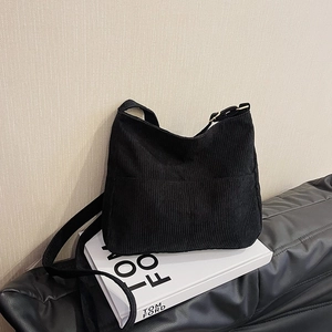 Minimalist black corduroy tote bag with adjustable shoulder strap and striped texture