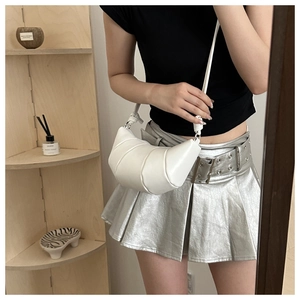 Détail du sac croissant blanc avec texture matelassée et détail de nœud sur la bandoulière
