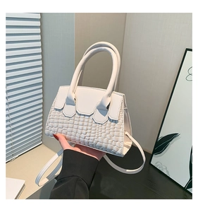 Dettaglio della borsa bianca con trama a coccodrillo e tracolla dal design minimalista