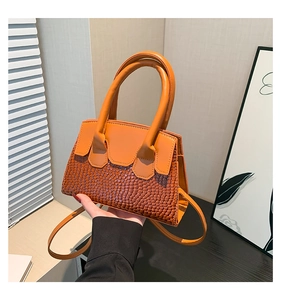 Dettaglio della borsa arancione che mostra la pelle liscia e il design patchwork a serpente