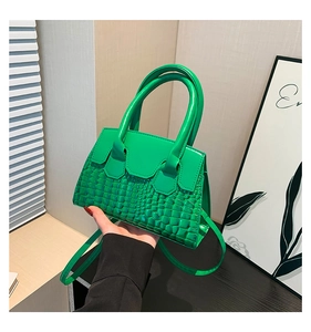 Dettaglio di mini borsa a mano verde brillante con trama a coccodrillo e manico liscio